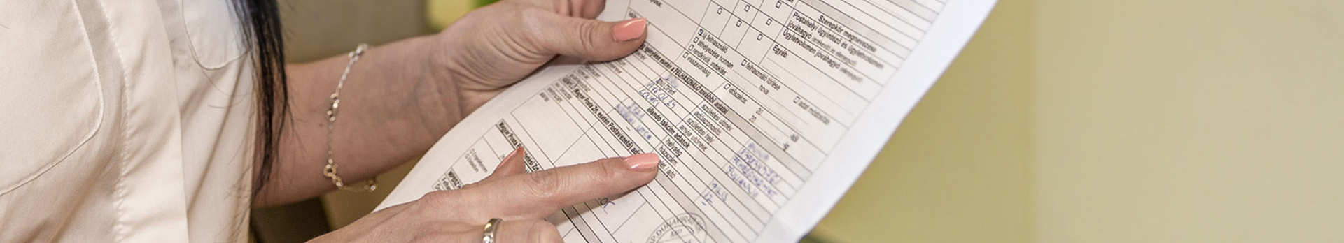 A képen egy nyomtatványt tartó nő látható.