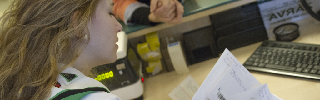 A képen egy ügyintéző hölgy látható, kezében levelekkel.