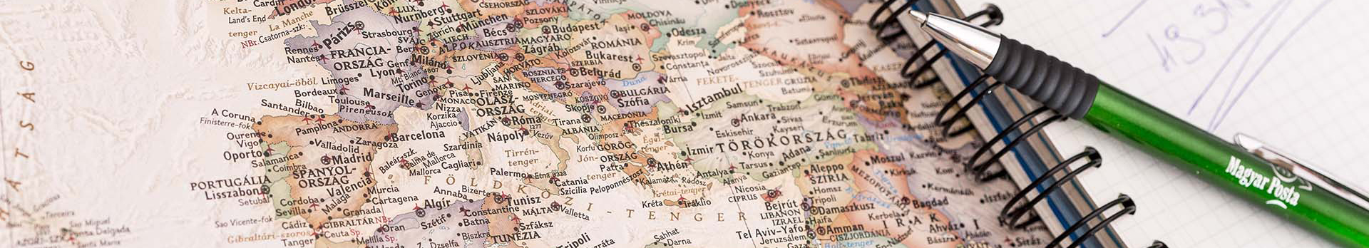 A képen egy országtérkép látható és egy füzet egy tollal.