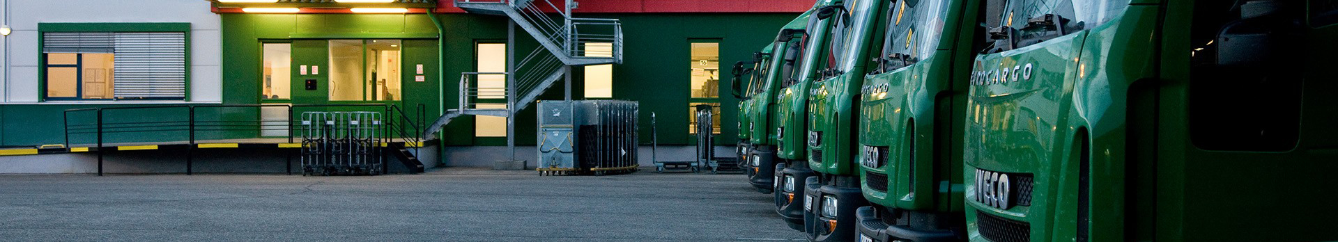 A képen egy raktárépület és az előtte látható kamionok láthatóak