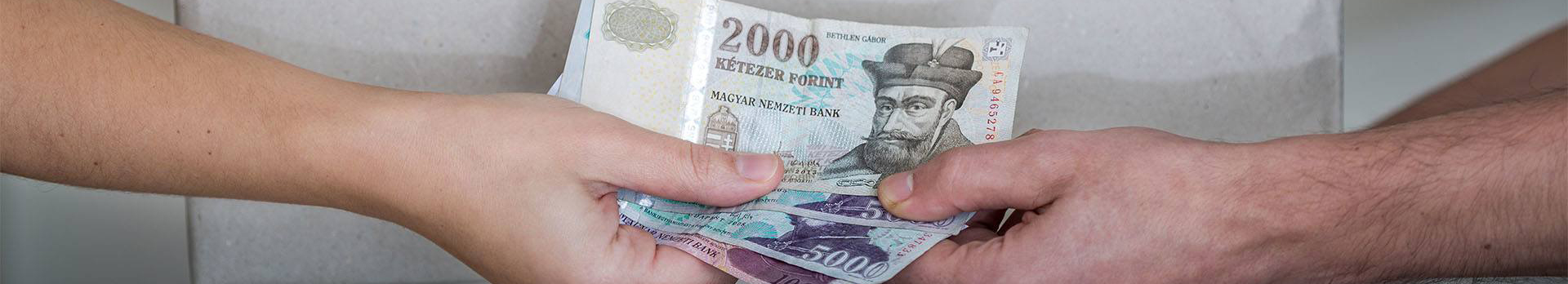 A képen egy csomag és egy bankjegyeket átnyújtó kéz látható.